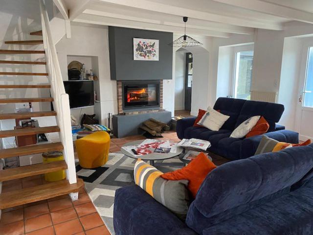 - un salon avec des canapés bleus et une cheminée dans l'établissement Aux Dix 'Jamet, à Tourville-sur-Sienne