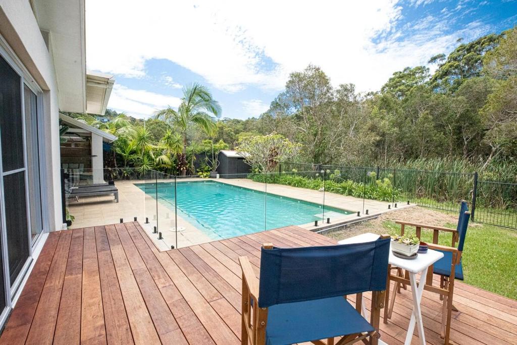 une cour arrière avec une piscine et une terrasse en bois dans l'établissement Harper House, à Suffolk Park