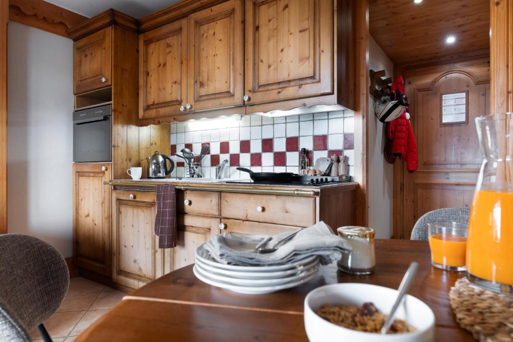 a kitchen with wooden cabinets and a table with food on it at Résidence Pierre & Vacances Premium Les Fermes De Méribel in Méribel