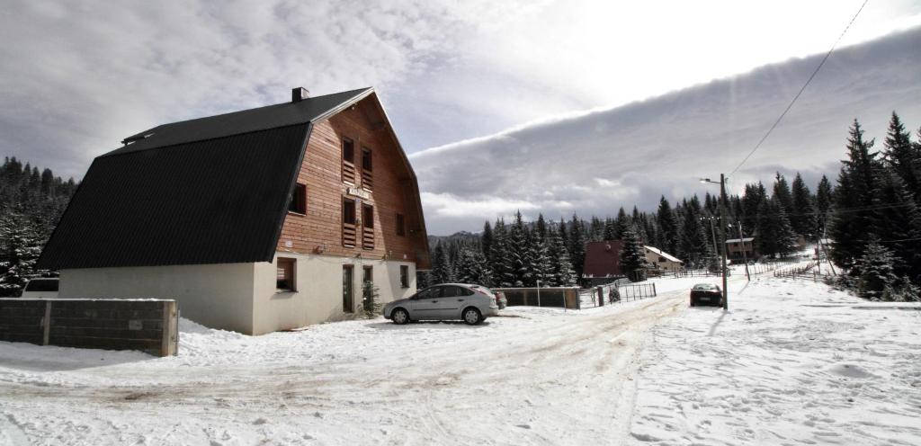 a car parked next to a barn in the snow at Guest House Alpha Ski Camp in Jahorina