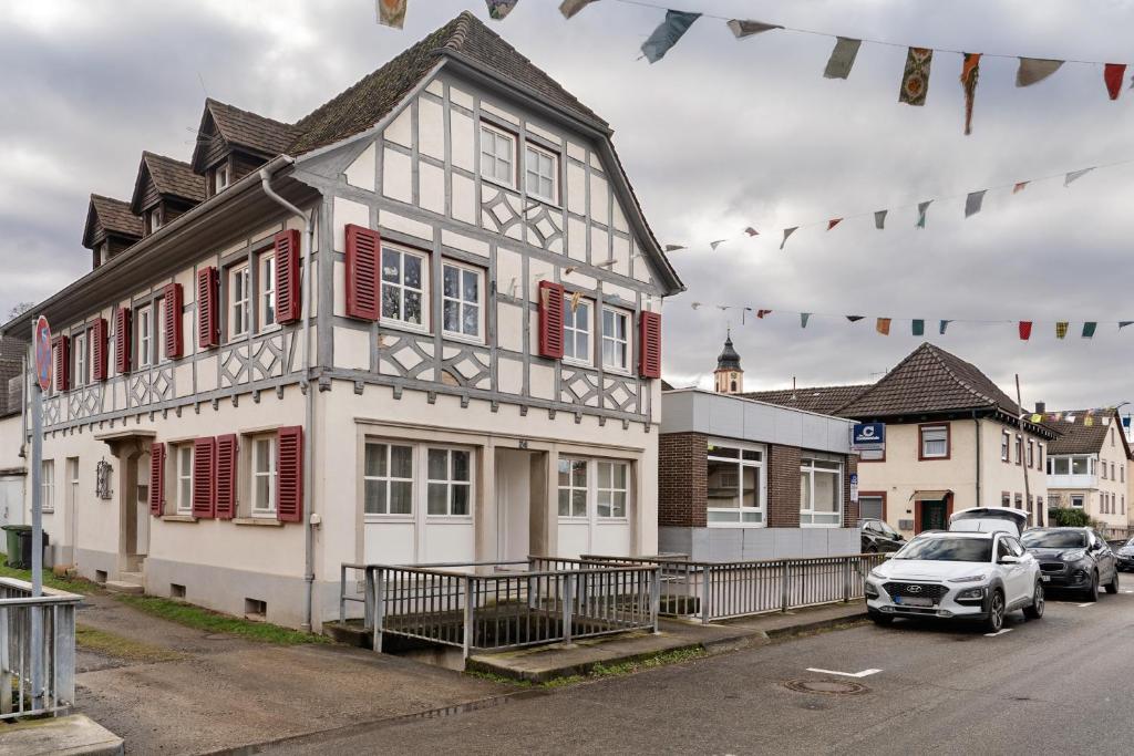 a white house with red shutters and a car parked in front at Ferienwohnung Merlin in Ettenheim