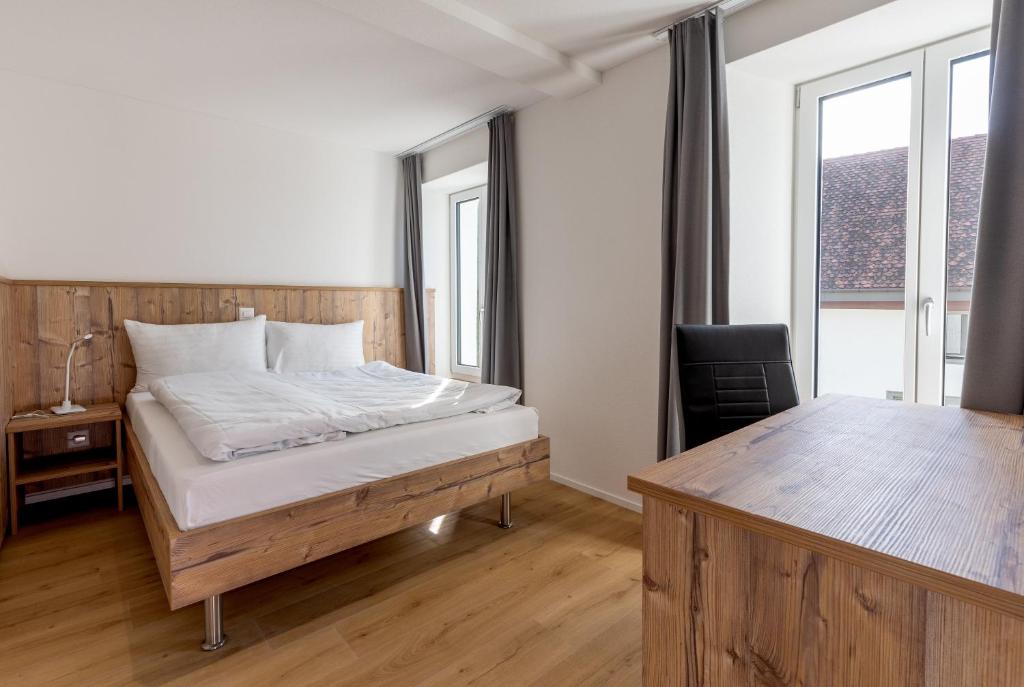a bedroom with a bed and a desk and windows at Hotel MeiSTAY - Self-Check-in in Meisterschwanden