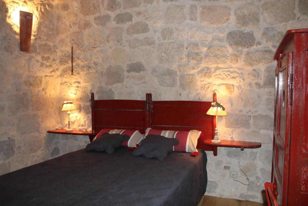 - une chambre avec un lit avec deux lampes et un mur en pierre dans l'établissement Chambre d'Hôtes La Tour de Brazalem, à Nérac