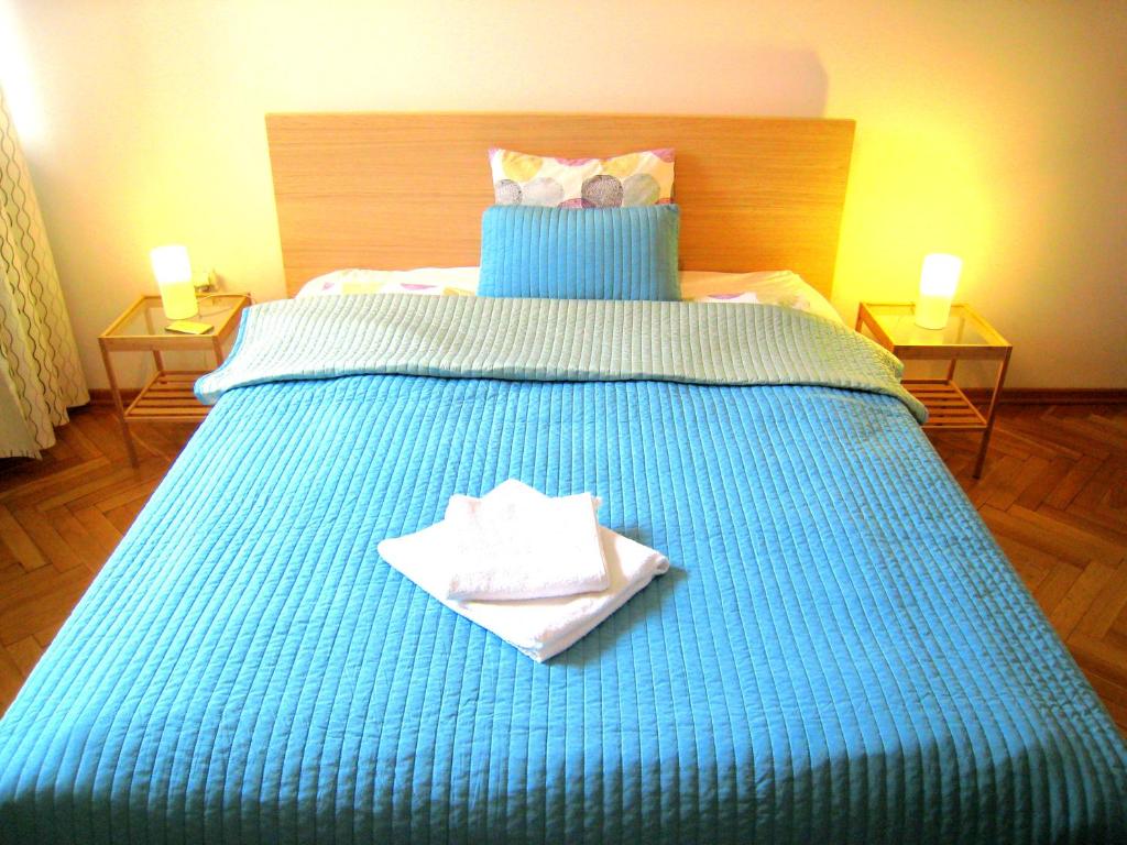 a blue bed with two towels on top of it at Wilson Apartment in Warsaw