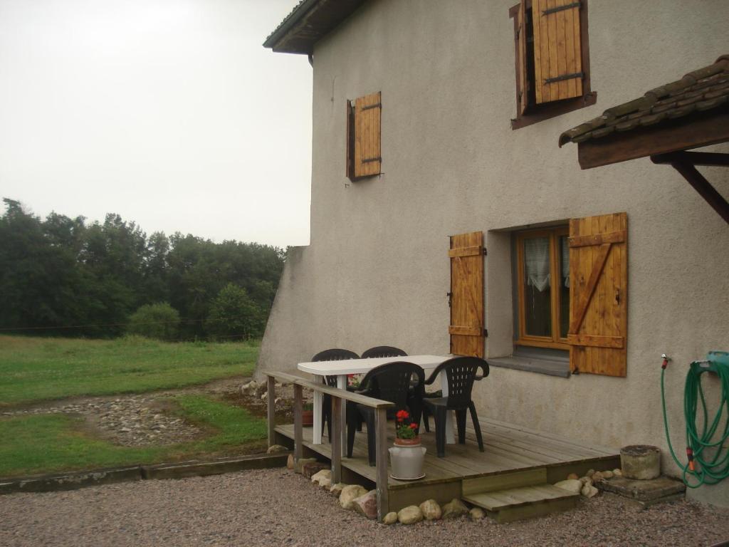 - une table et des chaises sur la terrasse couverte d'une maison dans l'établissement Maison à la campagne, à Paslières