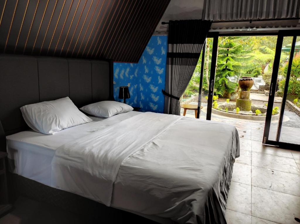 a bedroom with a large bed with white sheets at Goa Walet Cottage in Praya