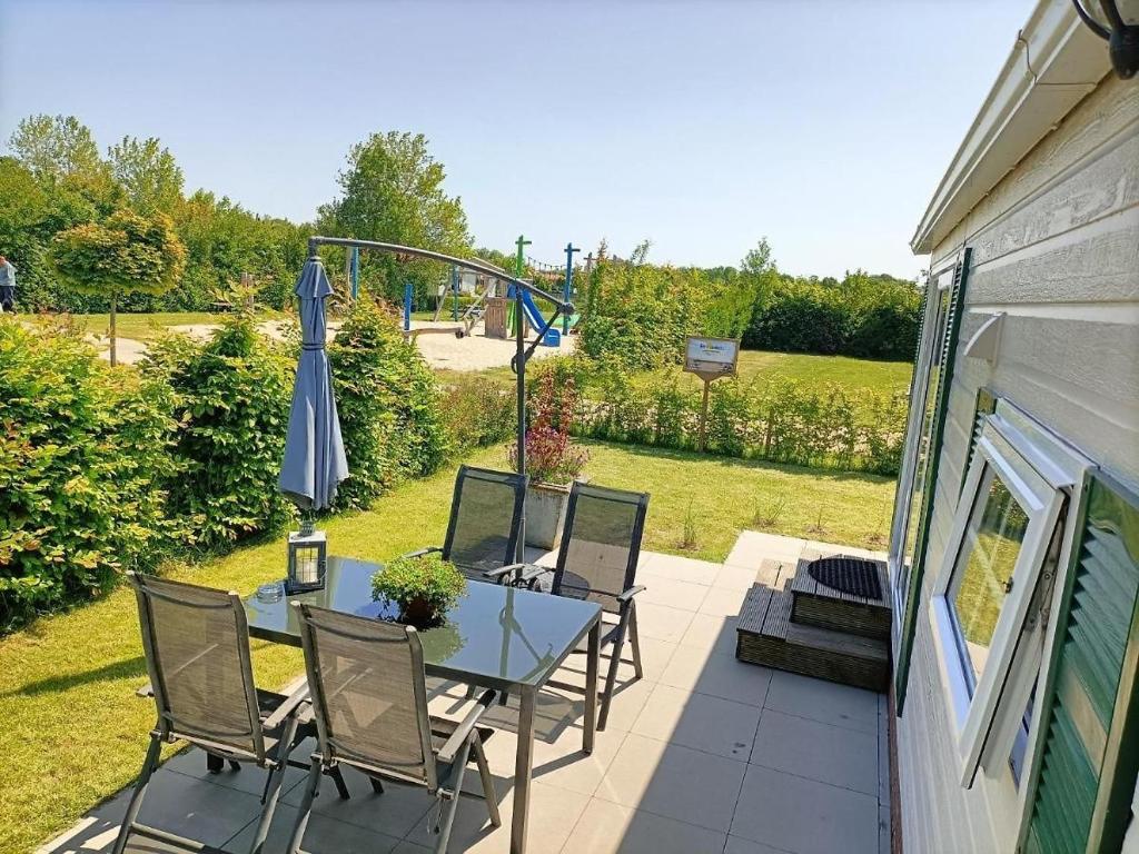 eine Terrasse mit Tisch, Stühlen und Sonnenschirm in der Unterkunft Do's Chalets in Baarland