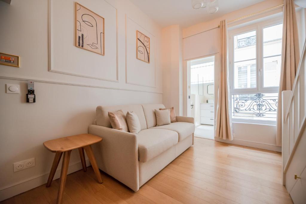 un salon avec un canapé blanc et une table dans l'établissement CIA - Mezzanine Studio by Arc de Triomphe, à Paris