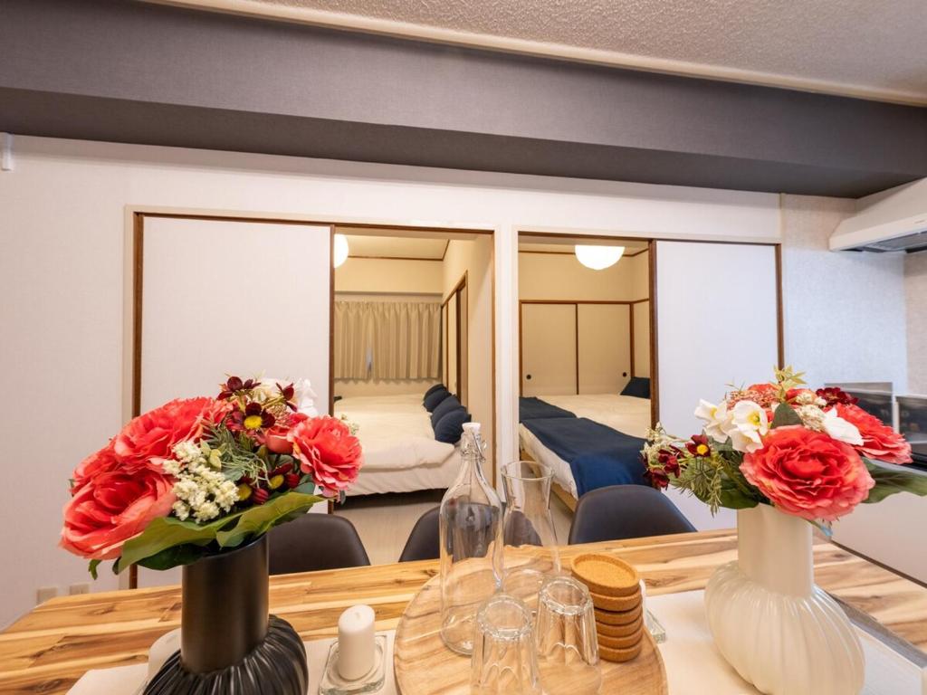 大阪MYB Namba 3BR suite close to Namba Self Check-In的一间设有一张桌子的房间,两瓶花花
