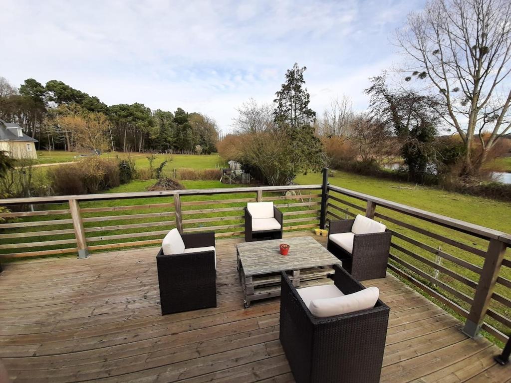 une terrasse en bois avec une table, des chaises et une clôture dans l'établissement Maison 8 pers proche Le Mans centre, circuit 24H et Boulerie JUMP, à Neuville-sur-Sarthe