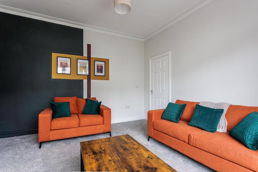 een woonkamer met 2 oranje stoelen en een tafel bij Modern 4-Bed Home Sleeps 6 in Stockton-on-Tees