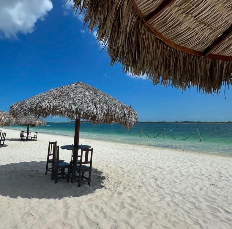 two chairs and a table under a straw umbrella on a beach at Apartamento Lagoa do Paraiso - Jericoacoara in Jijoca de Jericoacoara