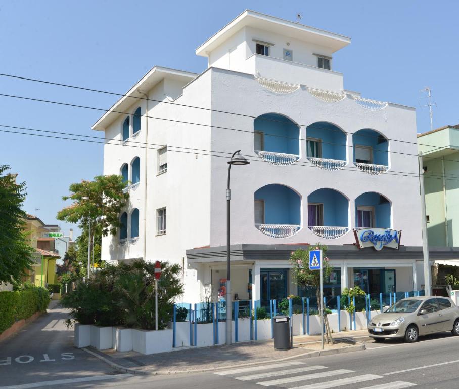 - un bâtiment blanc avec des balcons bleus dans une rue dans l'établissement Hotel Rosalba, à Riccione