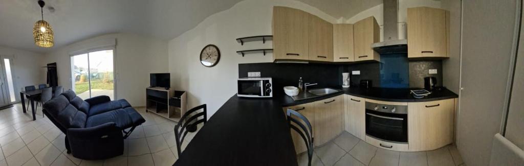 a kitchen with a counter and a living room at les tilleuls in Saint-Planchers