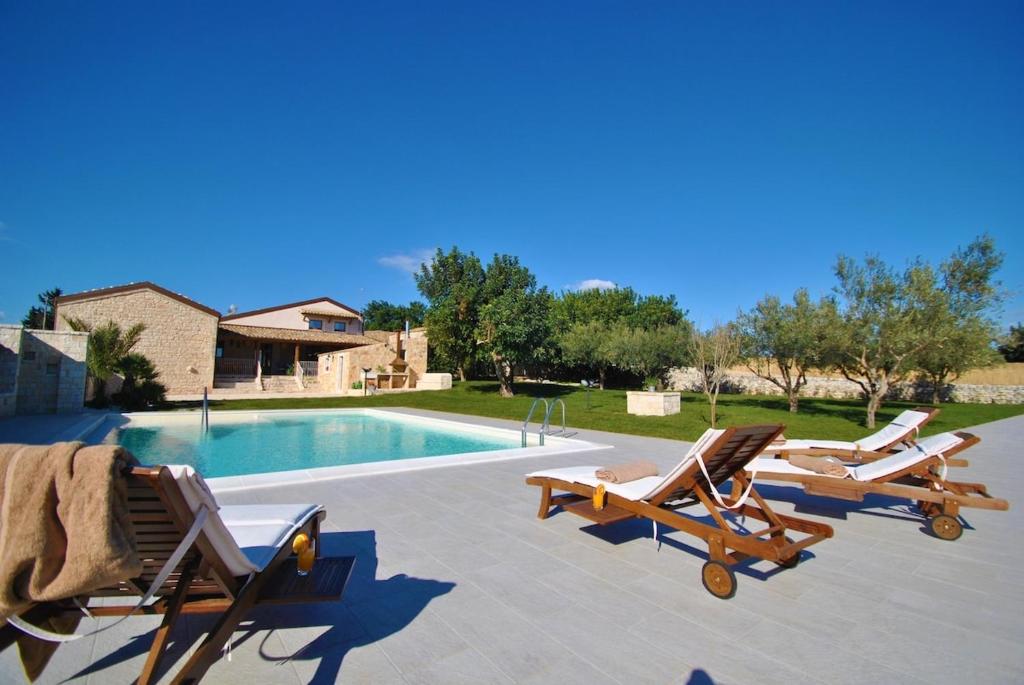 Un grupo de tumbonas y una piscina. en Casa Natia - IsulaTravel, en Módica