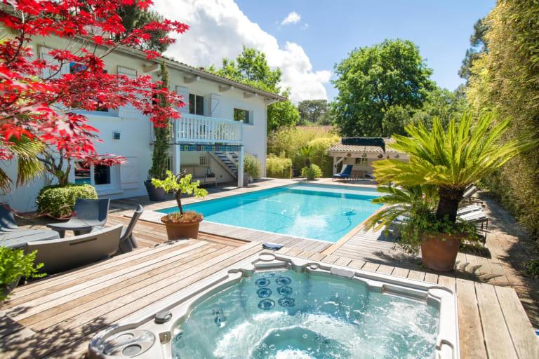 une cour arrière avec une piscine et une maison dans l'établissement Superbe villa de plage avec piscine chauffée et jacuzzi proche des plages, à La Teste-de-Buch