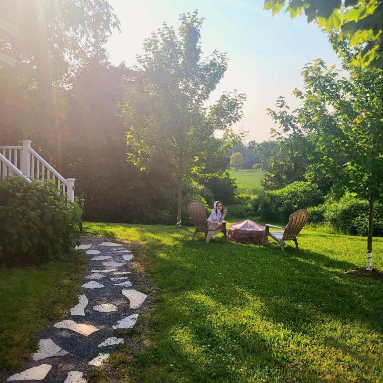 a woman sitting on two benches in a yard at The Pronghorn - 97 Butternut in Cherry Valley