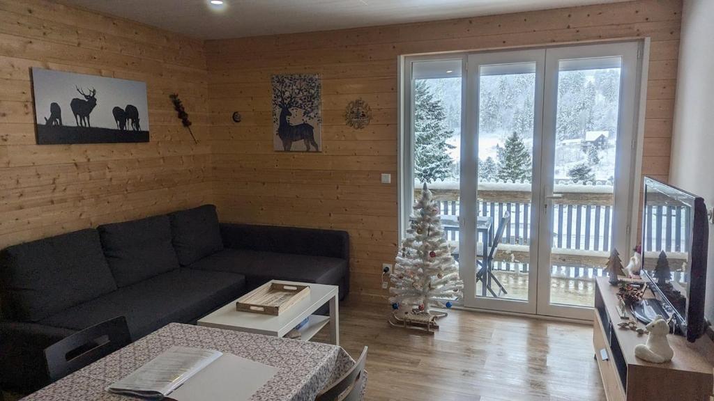 - un salon avec un canapé et un arbre de Noël dans l'établissement Appartement 3 étoiles, meublé, 45m2, station, fibre, Netflix, Disney plus, garage, à Laveissière