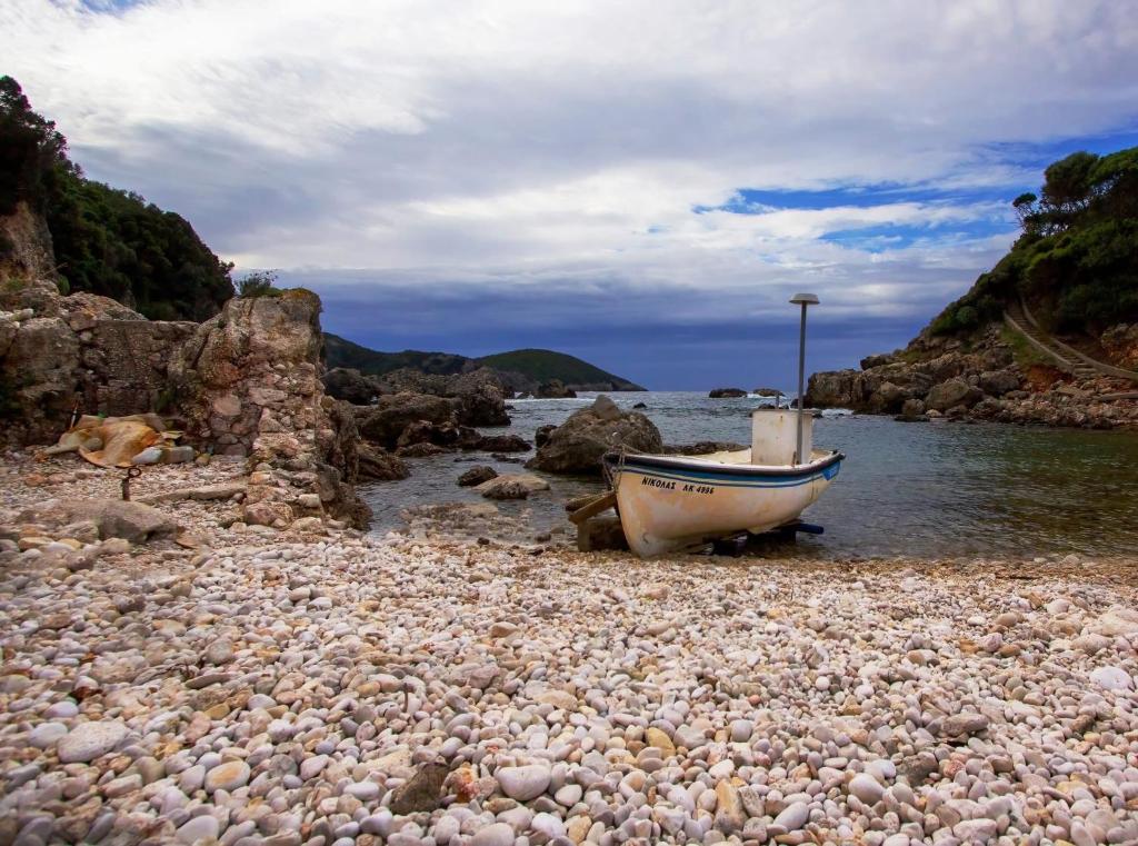 een boot op een rotsachtig strand naast het water bij Villa Maria 4 in Paleokastritsa