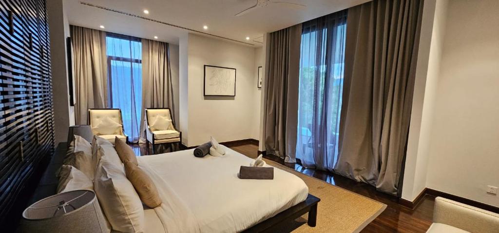 a bedroom with a bed and two chairs and windows at Villa Princess Stephanie in Kata Beach