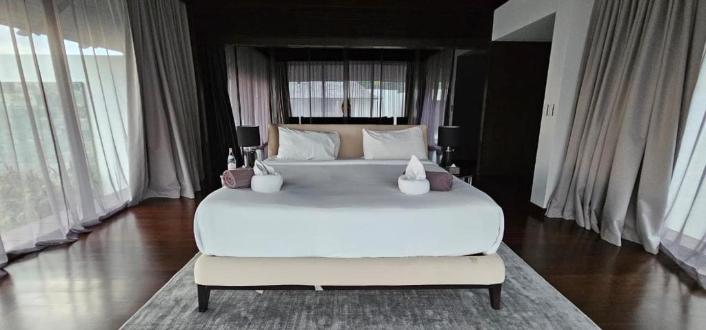 a large white bed in a room with windows at Villa Princess Stephanie in Kata Beach