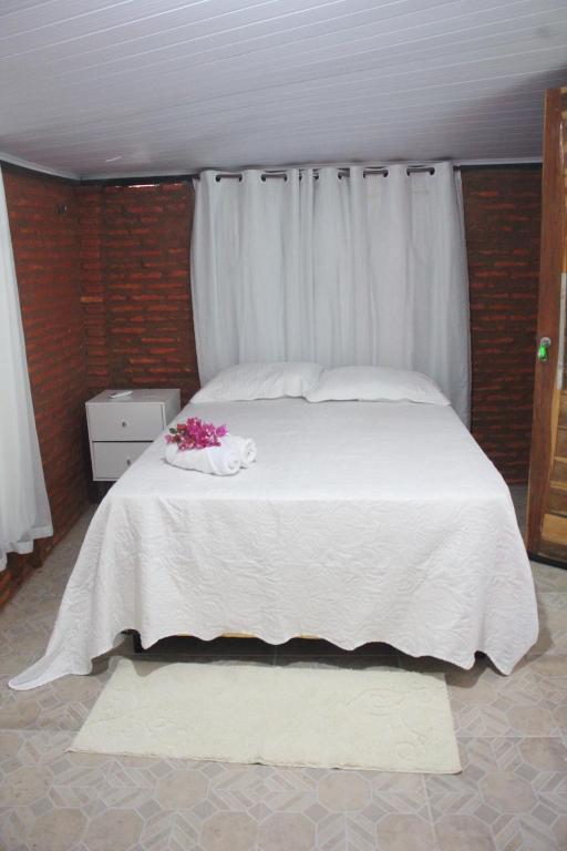 a bed with white sheets and pink flowers on it at Bom gosto tutoia in Tutóia