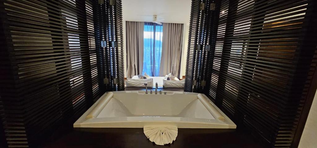 a bathroom with a bath tub in a room with windows at Villa Princess Stephanie in Kata Beach