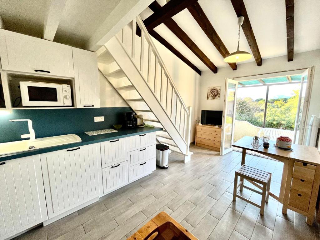 une cuisine avec des placards blancs, une table et un escalier dans l'établissement Appartement Studio Porticcio Paesolu 313, à Porticcio