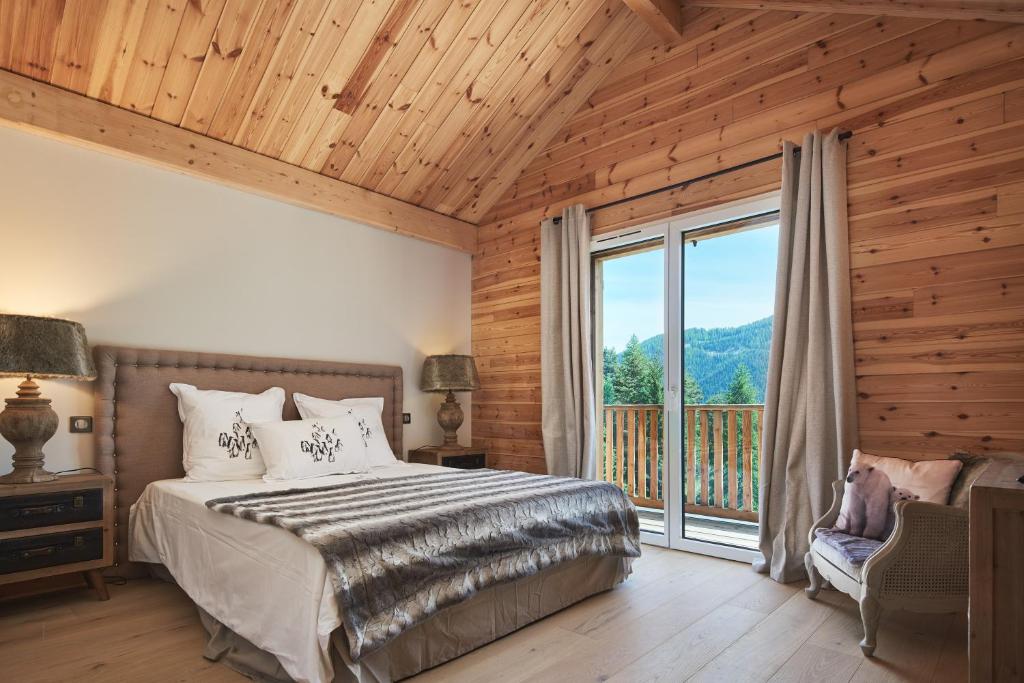 sypialnia z łóżkiem i dużym oknem w obiekcie Luxueux chalet avec terrasse Auron w mieście Saint-Étienne-de-Tinée