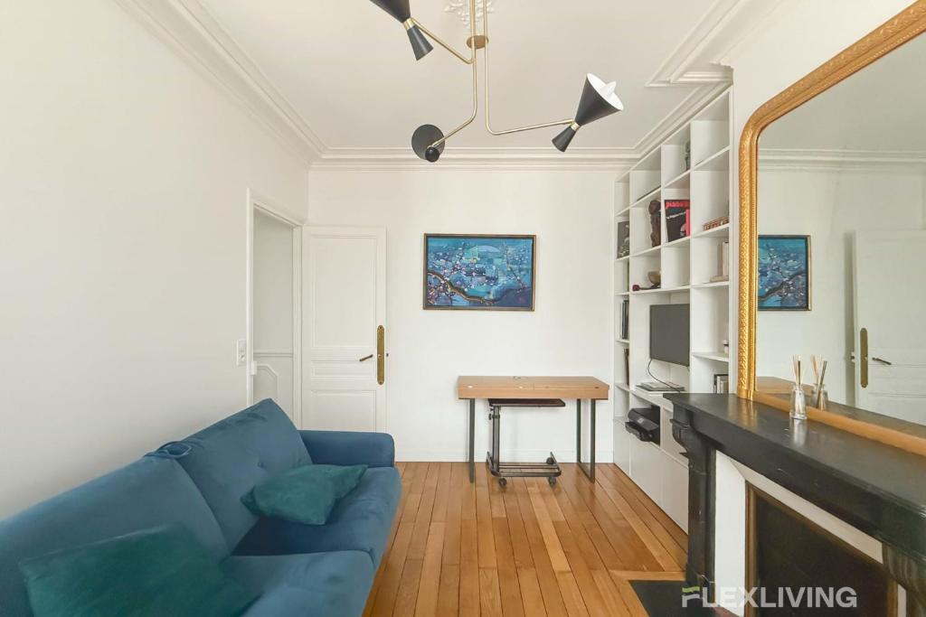 un salon avec un canapé bleu et une table dans l'établissement Flexliving - T2 - Eugène Gibez, à Paris