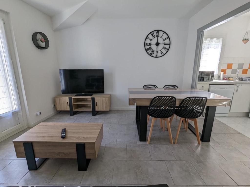 - un salon avec une table, des chaises et une télévision dans l'établissement Appartement cœur de ville, à Bessan