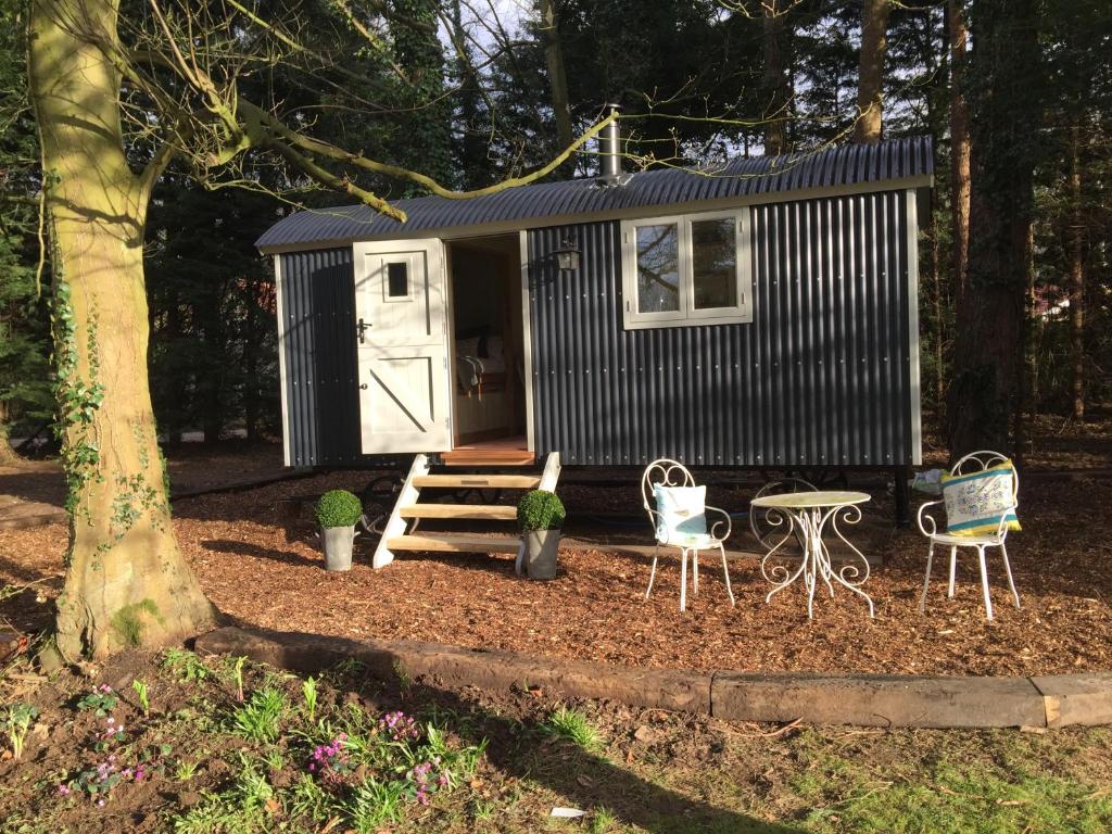 a black tiny house with a table and chairs at Chez Marguerite Luxury Shepherd's Hut in Holt