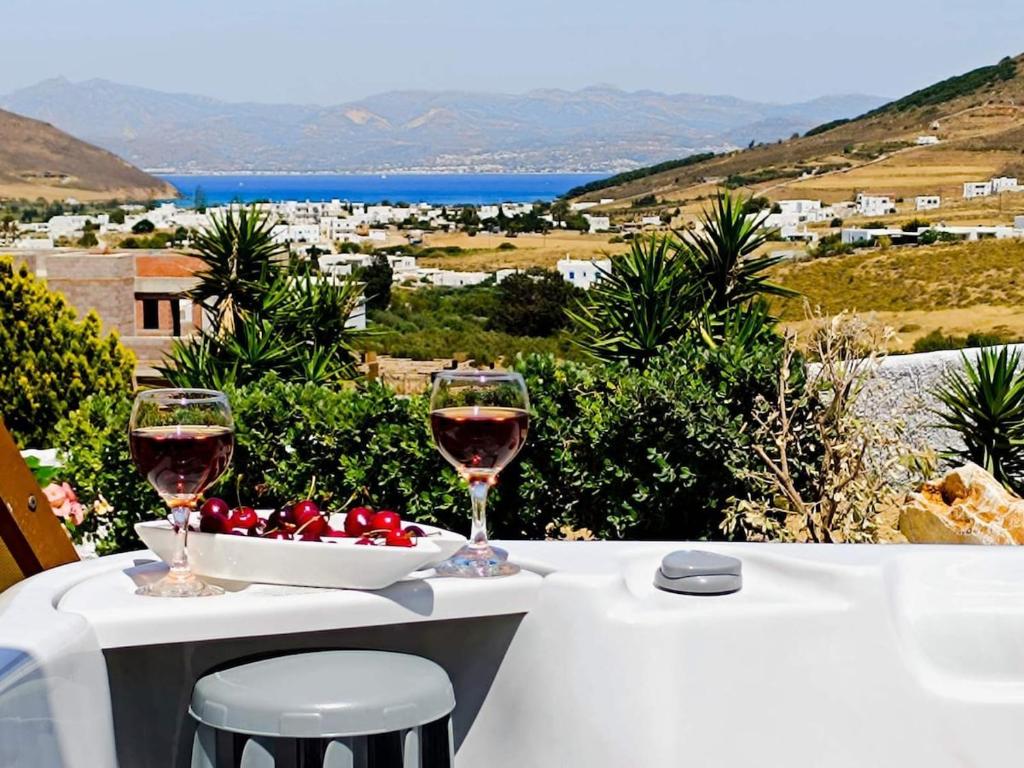 two glasses of wine and a bowl of tomatoes on a table at Irini's House Sunbeam in Dhragoulás