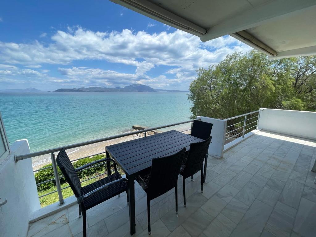 balkon ze stołem i krzesłami oraz oceanem w obiekcie Stunning Beachfront Apartment Strátos w mieście Nerántza