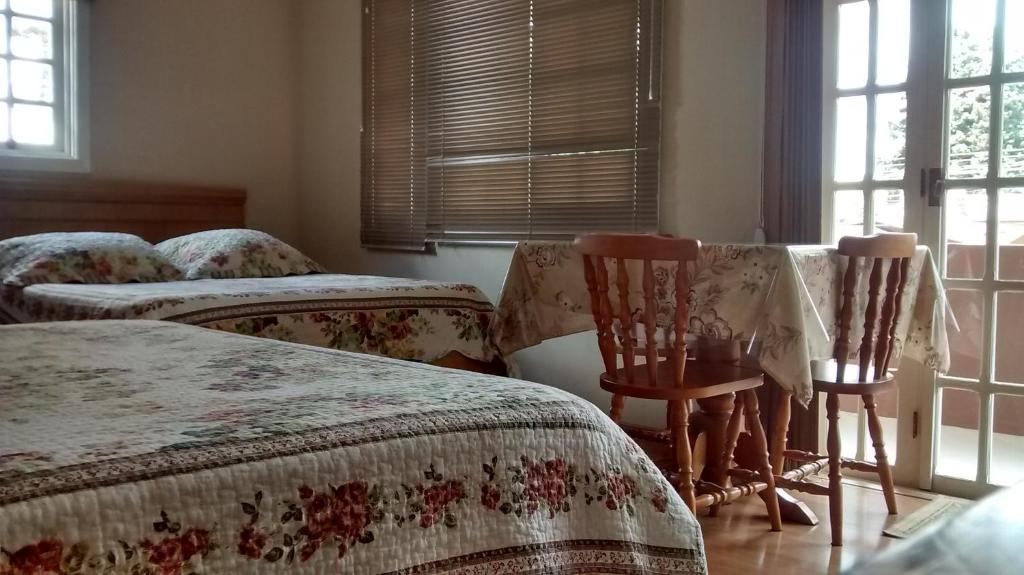 1 dormitorio con 2 camas, 2 sillas y ventanas en Estrelatto Residence en Gramado