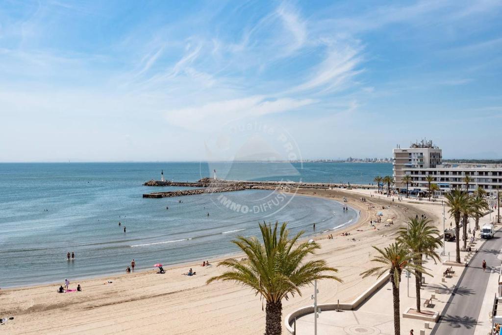 une vue sur une plage avec des palmiers et l'océan dans l'établissement AS21932 - Appartement P3 magnifique Vue Mer en dernier étage sur le Front de Mer, au Grau-du-Roi