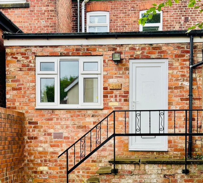 a brick building with a staircase and a white door at Cozy bungalow near Peak District in Stockport