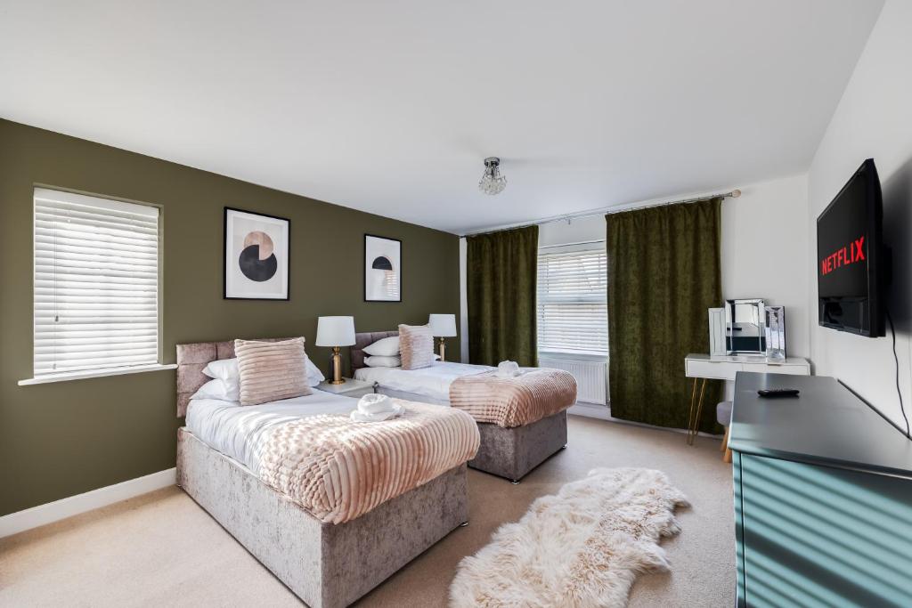 a bedroom with two beds and a tv in it at Stunning Detached House with Driveway Parking, Office Room, Self-Check-In, Fast WiFi and Smart TV with Sky and Netflix by Yoko Property in Milton Keynes
