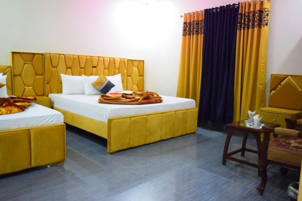 1 Schlafzimmer mit 2 Betten und gelben Vorhängen in der Unterkunft Royal Executive Residency in Islamabad