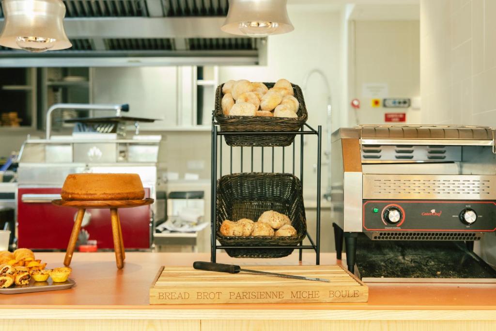 A breakfast counter displaying bread beside a commercial oven and open kitchen.