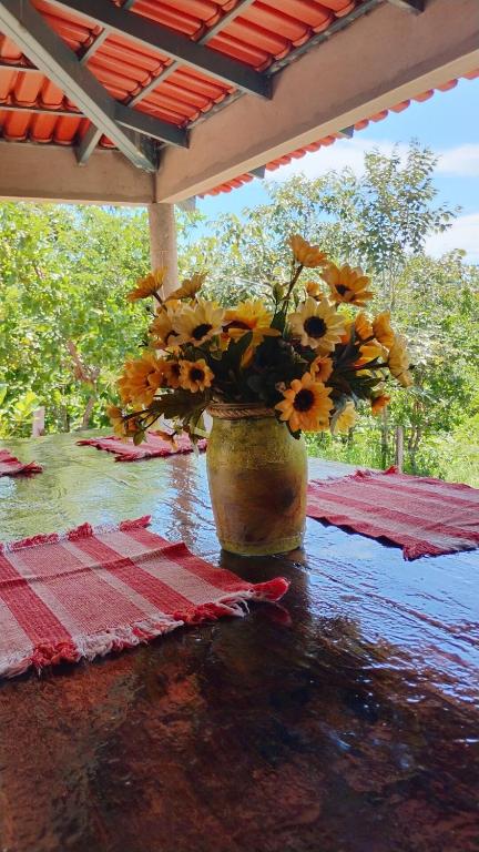 a vase filled with yellow flowers sitting on a table at CANTINHO DA ROSA ac - RIO PRIVATIVO in Manhã