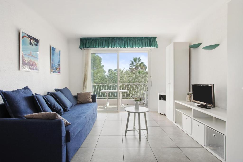 un salon avec un canapé bleu et une télévision dans l'établissement Le Studio Du Rivage - Saint Raphael, à Saint-Raphaël
