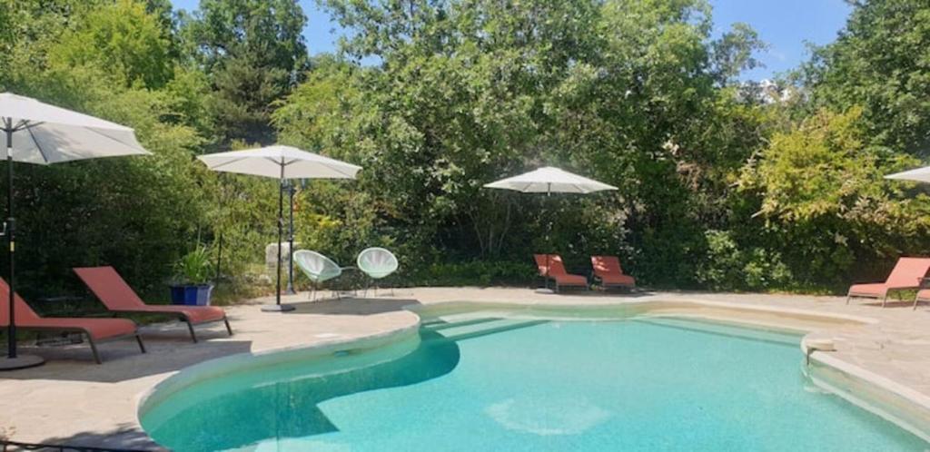 une piscine avec chaises et parasols dans l'établissement La Buisse - Les 2 Gites, à Simiane-la-Rotonde