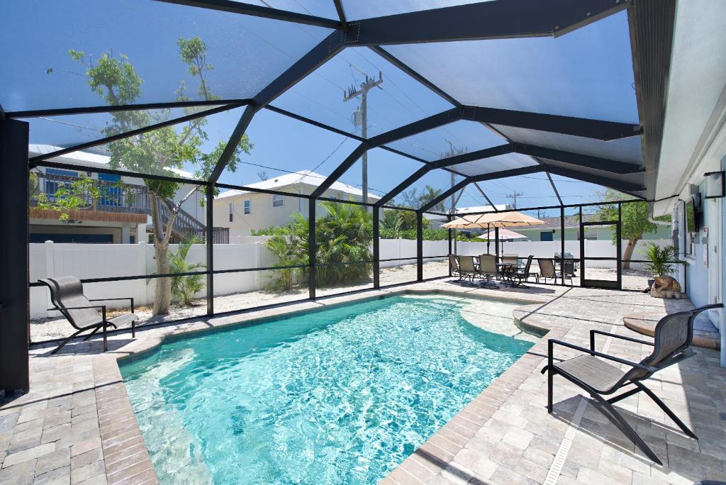 a swimming pool with an umbrella and chairs at Ocean Breeze by Sun Palace Vacations in Fort Myers Beach