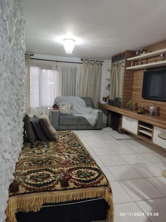 a living room with a bed and a television at Sobrado terreo aconchegante in Capão da Canoa