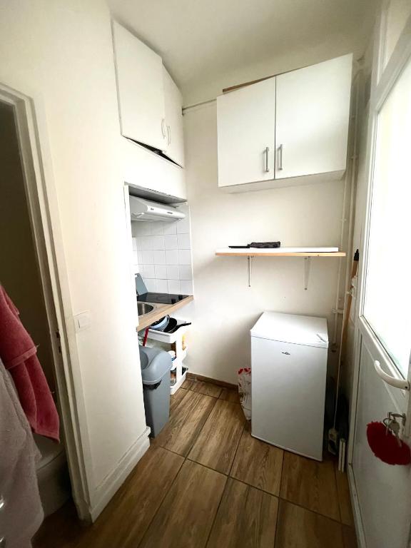 Elle comprend une petite cuisine avec des placards blancs et du parquet. dans l'établissement Studio 20m2, à Drancy