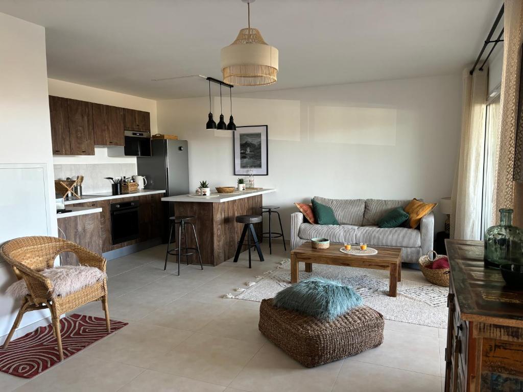un salon avec un canapé et une cuisine dans l'établissement SEJOUR DE CHARME A CALVI vue mer et montagne en T3 résidentiel avec piscine, à Calvi