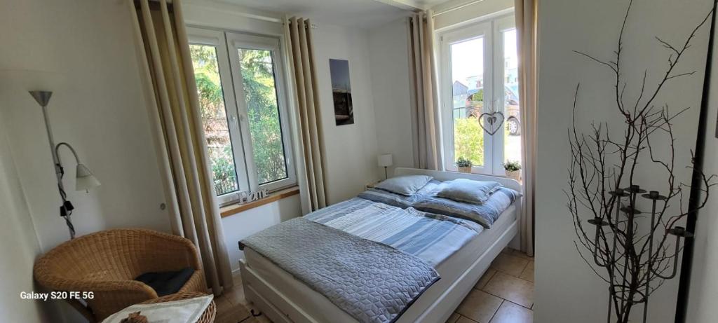 a small bedroom with a bed and two windows at Dom letniskowy nad jeziorem Wigry Staw Suwalszczyzna in Suwałki