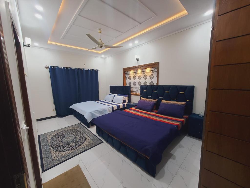 a bedroom with two beds and a ceiling fan at Kashees Lodges in Islamabad