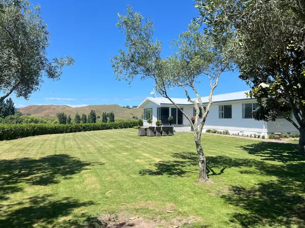 a white house with a tree in the yard at Wineries and cycle tracks on your doorstep in Havelock North